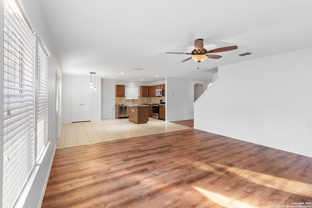 unfurnished living room featuring ceiling fan, light hardwood / wood-style flooring, and sink