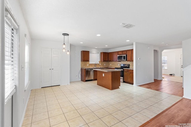 kitchen featuring a kitchen island, sink, hanging light fixtures, appliances with stainless steel finishes, and light tile patterned floors