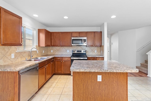 kitchen featuring light tile patterned floors, appliances with stainless steel finishes, backsplash, a kitchen island, and sink