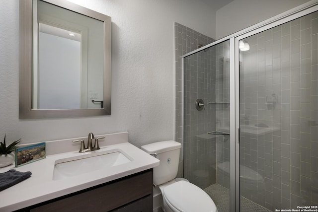 bathroom with toilet, vanity, and a shower with door