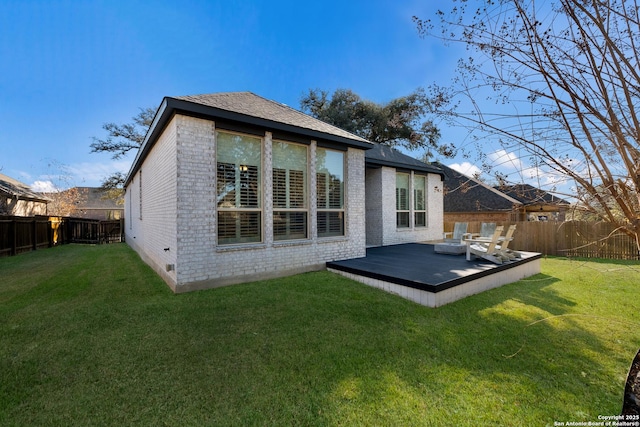 back of property featuring a wooden deck and a yard