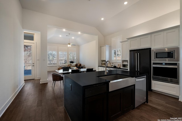 kitchen with lofted ceiling, ceiling fan, a center island with sink, white cabinetry, and stainless steel appliances