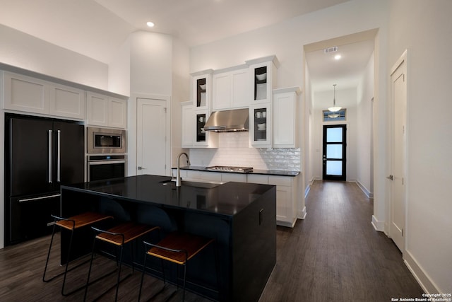 kitchen featuring a breakfast bar, white cabinetry, stainless steel appliances, and a kitchen island with sink