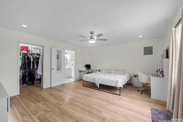 bedroom with ceiling fan, connected bathroom, a closet, electric panel, and light hardwood / wood-style flooring