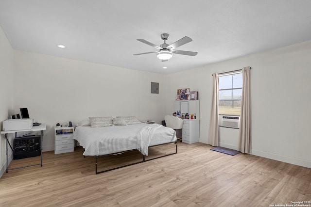 bedroom with ceiling fan, electric panel, and light hardwood / wood-style flooring