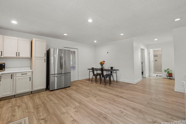 kitchen featuring light hardwood / wood-style floors, white cabinetry, appliances with stainless steel finishes, and a textured ceiling