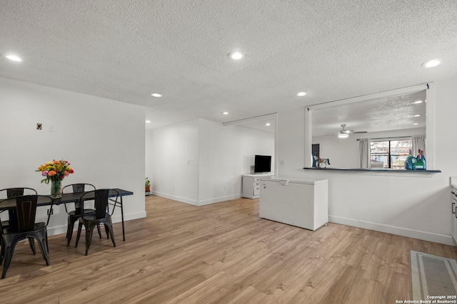 kitchen featuring a textured ceiling, white cabinetry, light hardwood / wood-style floors, kitchen peninsula, and ceiling fan