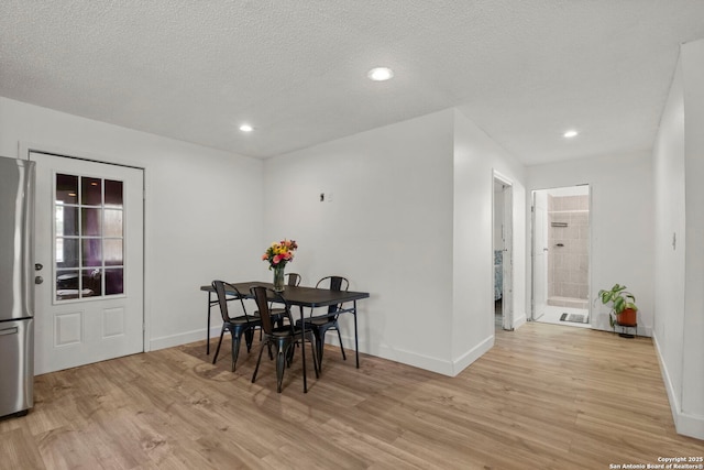 dining area featuring a textured ceiling and light wood-type flooring