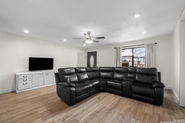 living room with ceiling fan, a textured ceiling, and light wood-type flooring