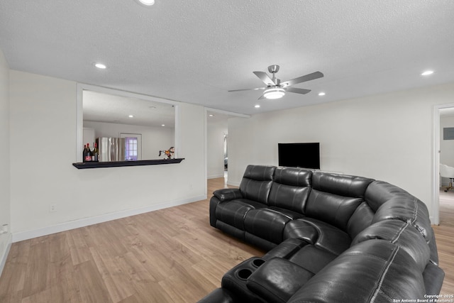 living room with ceiling fan, a textured ceiling, and light hardwood / wood-style floors