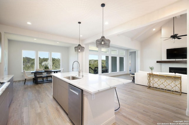 kitchen with decorative light fixtures, dishwasher, sink, a kitchen island with sink, and light stone countertops