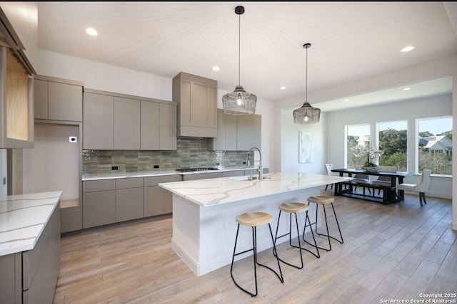 kitchen featuring gray cabinetry, tasteful backsplash, a spacious island, stainless steel gas cooktop, and sink