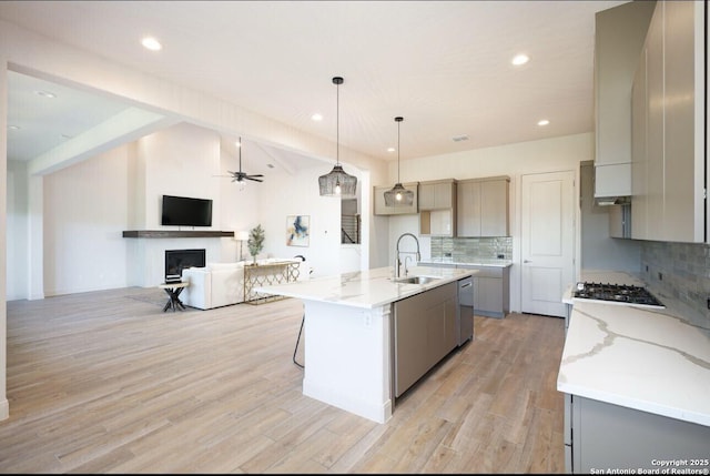 kitchen with pendant lighting, a large island with sink, tasteful backsplash, sink, and gray cabinetry