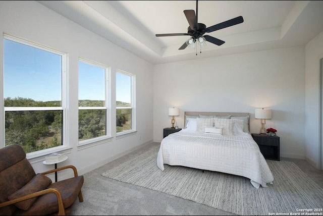 carpeted bedroom featuring ceiling fan and a raised ceiling