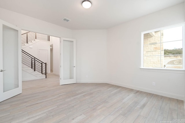 empty room with light hardwood / wood-style flooring, french doors, and a healthy amount of sunlight