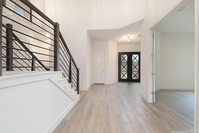 foyer entrance with french doors and light hardwood / wood-style flooring