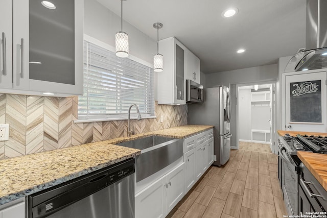 kitchen with stainless steel appliances, backsplash, decorative light fixtures, white cabinets, and sink