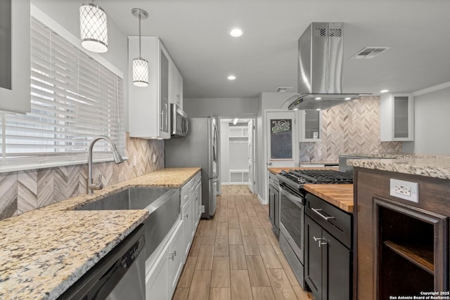 kitchen featuring island exhaust hood, stainless steel appliances, backsplash, decorative light fixtures, and white cabinets