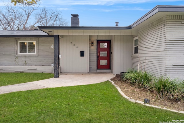 view of exterior entry featuring a lawn