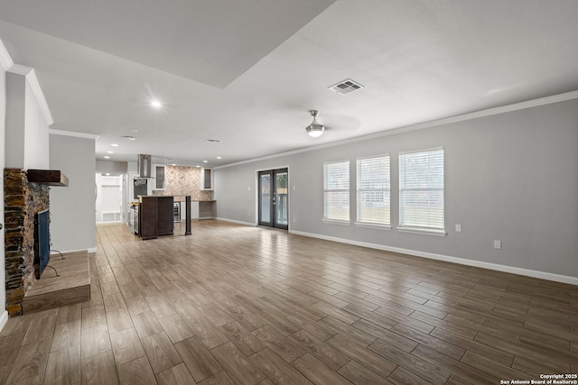 unfurnished living room with ceiling fan, ornamental molding, and a stone fireplace