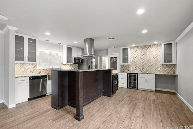 kitchen featuring light stone counters, white cabinetry, island range hood, and stainless steel appliances