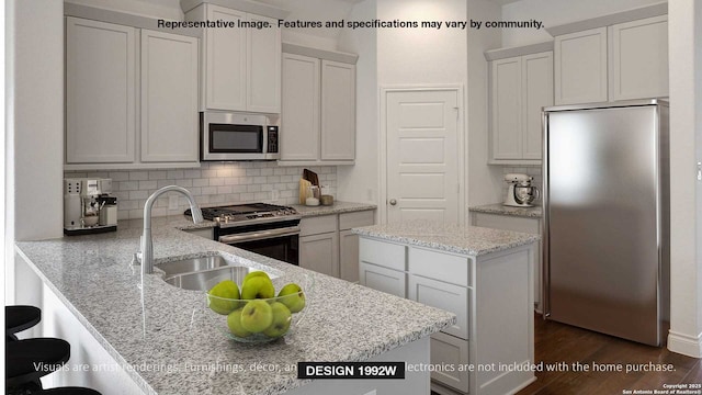 kitchen featuring backsplash, sink, appliances with stainless steel finishes, white cabinets, and light stone counters