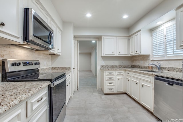 kitchen featuring light stone countertops, sink, stainless steel appliances, and white cabinetry