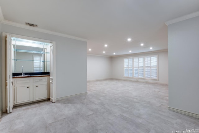 unfurnished living room featuring indoor wet bar and ornamental molding