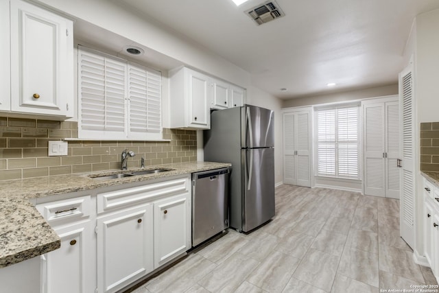 kitchen featuring light stone counters, sink, white cabinets, and stainless steel appliances