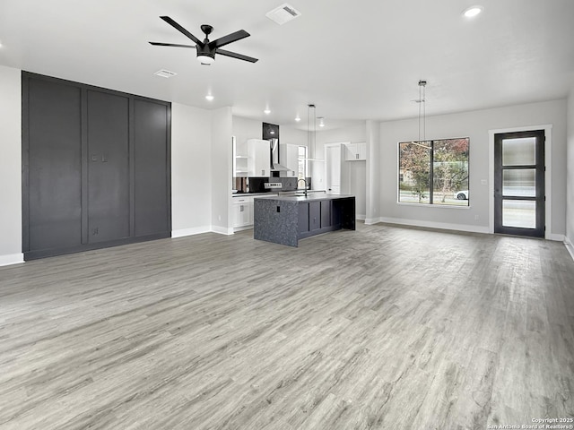 unfurnished living room with ceiling fan, light hardwood / wood-style floors, and sink