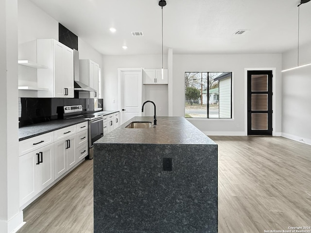 kitchen with stainless steel electric stove, pendant lighting, white cabinets, an island with sink, and sink