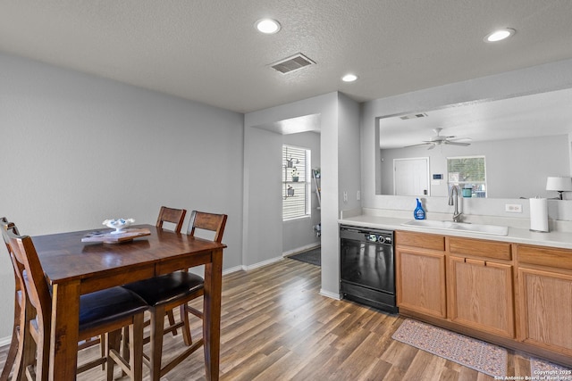 kitchen with a textured ceiling, black dishwasher, sink, dark hardwood / wood-style floors, and ceiling fan