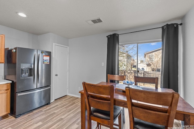 dining area featuring light wood-type flooring and a textured ceiling