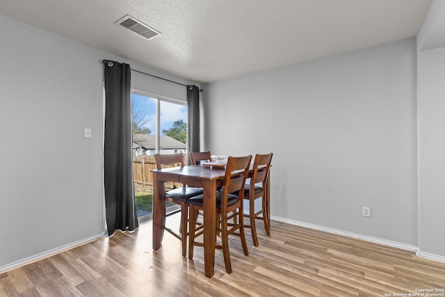 dining space with light wood-type flooring and a textured ceiling