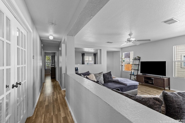 living room featuring ceiling fan, dark hardwood / wood-style flooring, and a textured ceiling