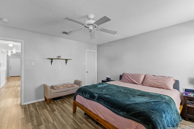 bedroom with a textured ceiling, ceiling fan, and wood-type flooring