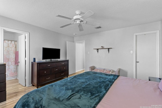 bedroom with ceiling fan, connected bathroom, a textured ceiling, and light wood-type flooring