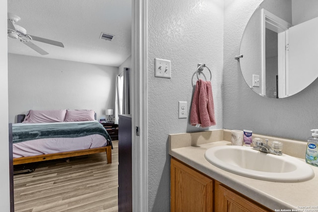 bathroom with ceiling fan, a textured ceiling, wood-type flooring, and vanity