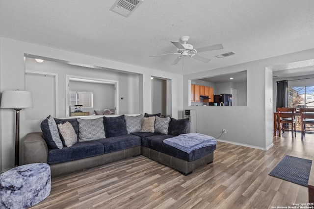 living room featuring a textured ceiling, ceiling fan, and hardwood / wood-style floors