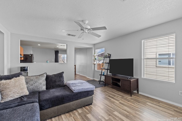 living room featuring a textured ceiling, ceiling fan, and light hardwood / wood-style floors