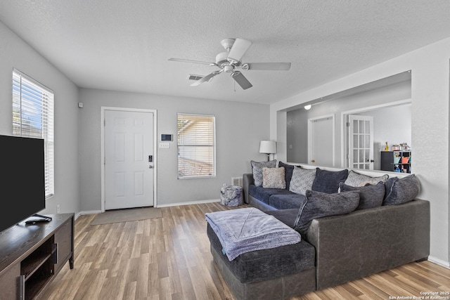 living room with a textured ceiling, ceiling fan, and wood-type flooring