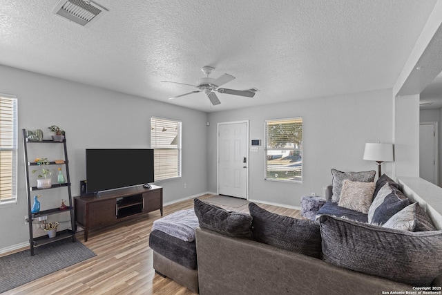 living room with light wood-type flooring, ceiling fan, and a textured ceiling