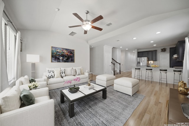 living room featuring ceiling fan, light wood-type flooring, and vaulted ceiling