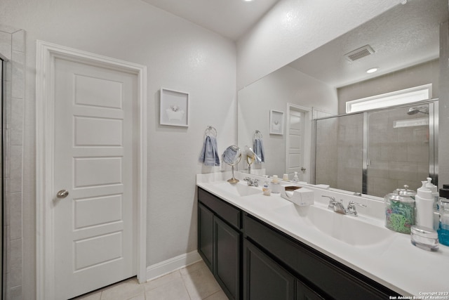 bathroom featuring tile patterned flooring, a shower with shower door, and vanity