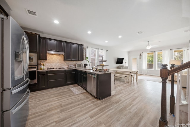 kitchen with appliances with stainless steel finishes, light hardwood / wood-style floors, decorative backsplash, kitchen peninsula, and ceiling fan