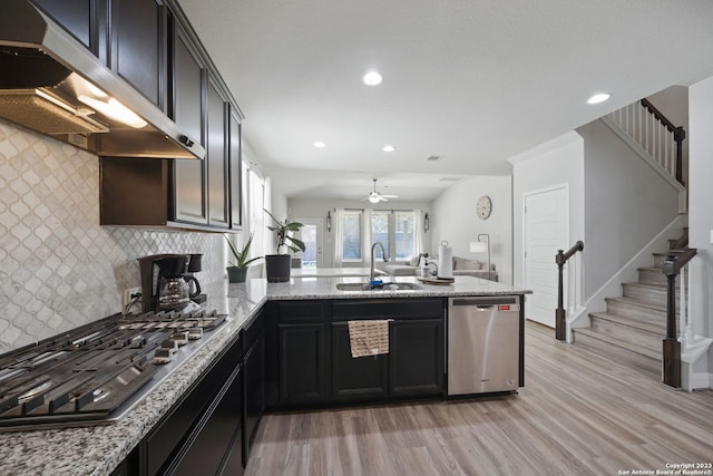 kitchen with tasteful backsplash, light hardwood / wood-style floors, sink, stainless steel appliances, and light stone counters