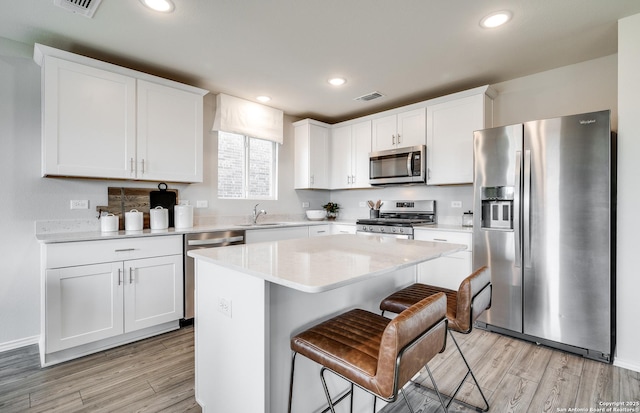 kitchen with sink, white cabinets, a center island, and stainless steel appliances