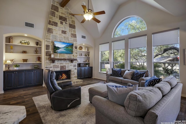 living room featuring built in shelves, dark hardwood / wood-style flooring, a stone fireplace, and a wealth of natural light