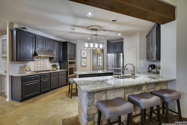 kitchen featuring sink, a kitchen breakfast bar, light stone counters, kitchen peninsula, and stainless steel appliances