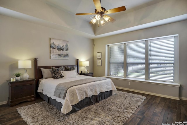 bedroom featuring a tray ceiling, dark wood-type flooring, and ceiling fan